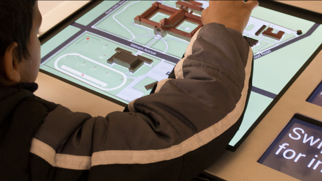 A person using a tactile interactive map display that combines touch and digital interface.