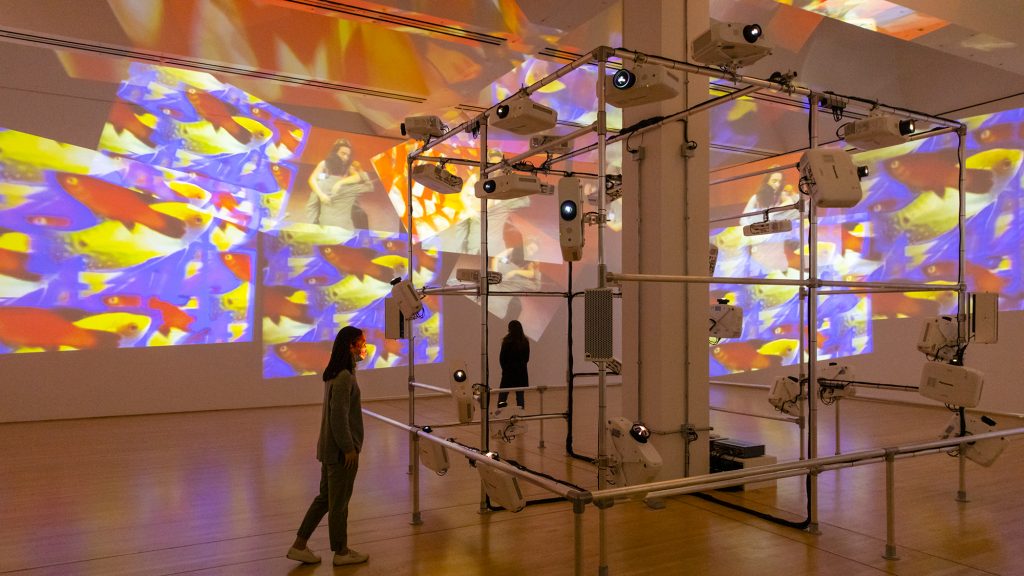 projections covering gallery walls with a metal structure holding the projectors in the centre of room