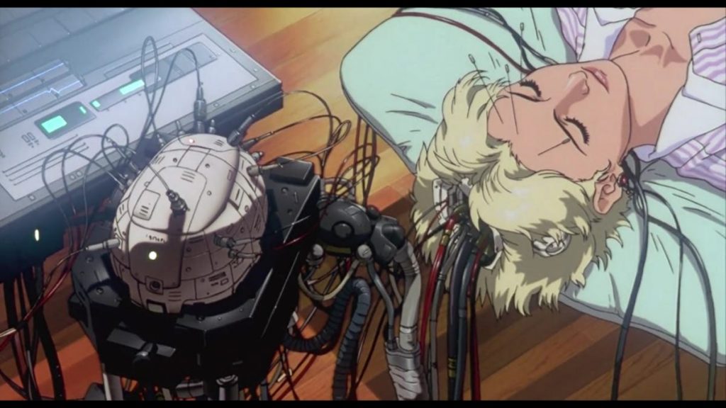 An animated woman lying down with what appears to be an artificial brain next to her, with wires and cables connected to it that are attached to her body via the top of her head