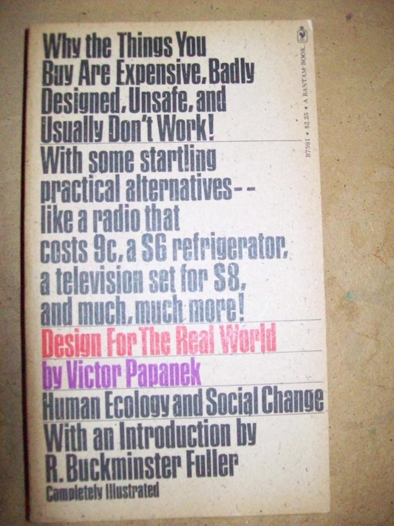 A photograph of the vintage book cover of Design for the Real World by Victor Papanek. The cover features dense, bold sans-serif typography in multiple colours—black, grey, red, and purple—stacked vertically in a left-aligned layout. The text highlights the book’s provocative tagline about poorly designed consumer products, followed by descriptions of practical alternatives. The title “Design For The Real World” appears in bright red, with the author’s name in purple beneath it. Additional text notes the subtitle “Human Ecology and Social Change” and mentions an introduction by R. Buckminster Fuller. The background is light beige, with a slightly aged, textured appearance.