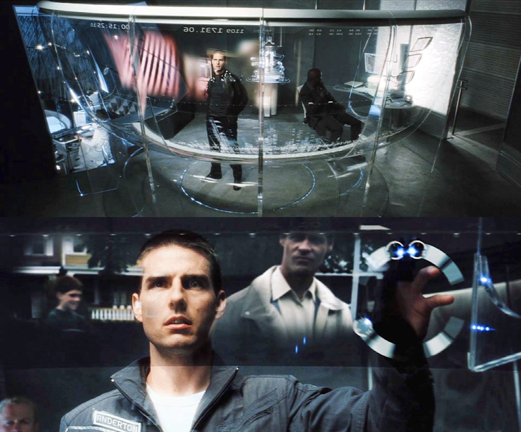 Scene from Minority Report (2002) Futuristic lab with transparent screens where a focused man (Tom Cruise's character) interacts with holographic displays